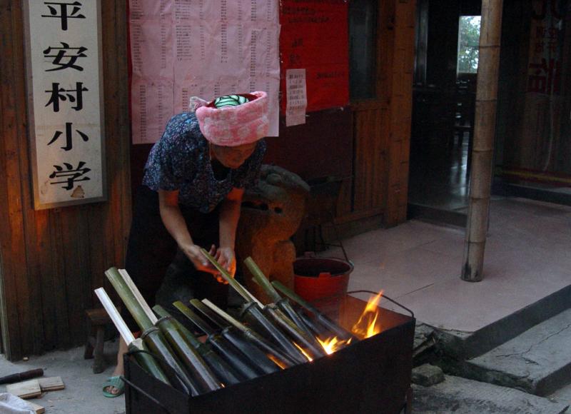 Zhuang woman cooking rice in bamboo